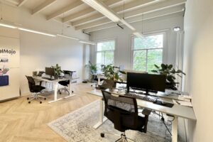 Modern kantoorinterieur aan de Paulus Potterstraat met meerdere werkplekken, grote ramen en veel groen.